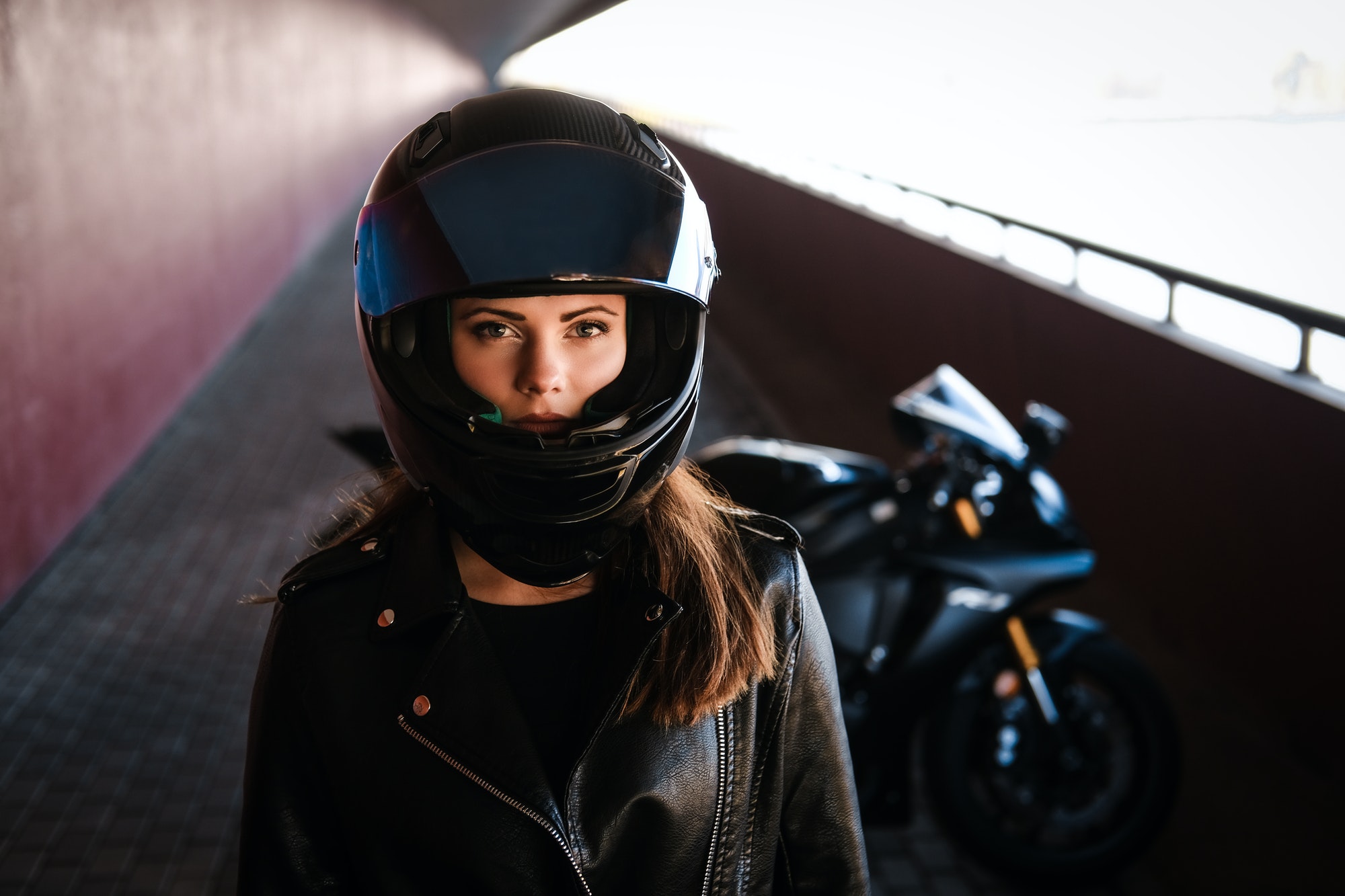 Attractive serious woman is standing next to her motobike