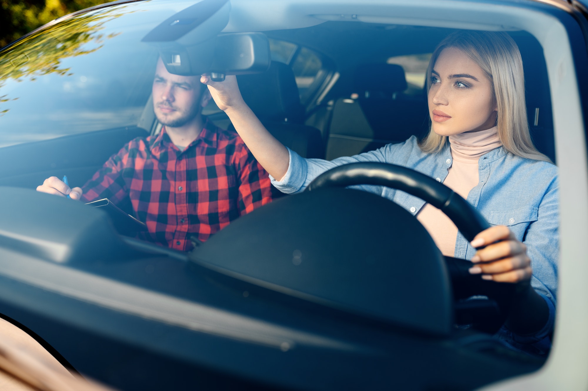 Lady and male instructor in car, driving school